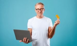 Imagem de homem com computador e cartão representando bancos digitais com cartão de crédito para negativados